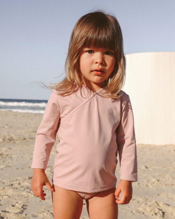 Ada, a little girl, wearing an Ada Rash Shirt on the beach.