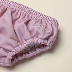 A close up of a pink Lumi Brief Swim Nappy on a white surface.