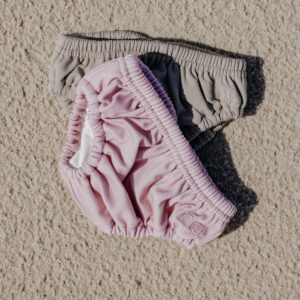 A pair of Lumi Brief Swim Nappy on a sand surface.