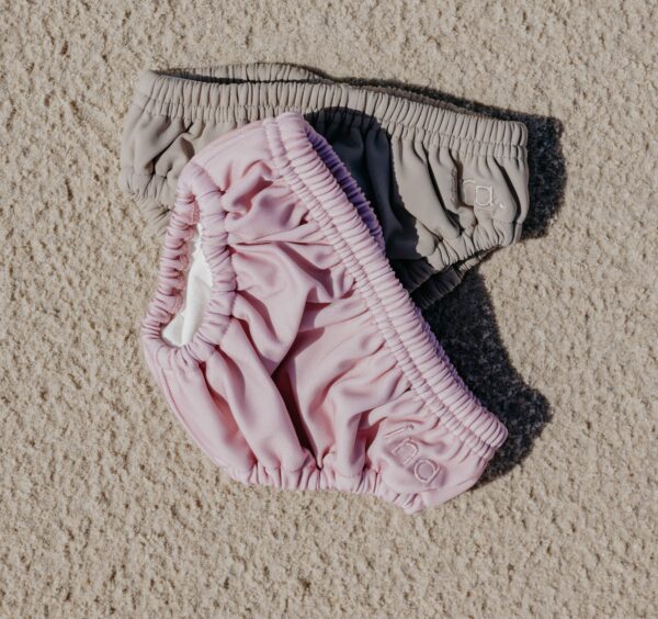 A pair of Lumi Brief Swim Nappy on a sand surface.