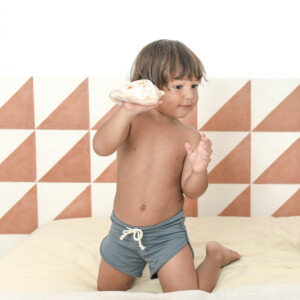 A young boy playing with Mesa Trunks on a bed.