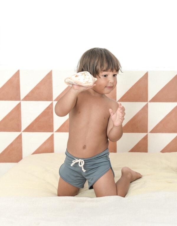 A young boy playing with Mesa Trunks on a bed.