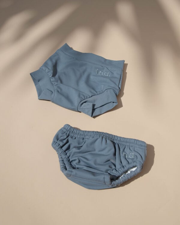 A pair of Lumi Brief Swim Nappy on a table with a palm tree in the background.