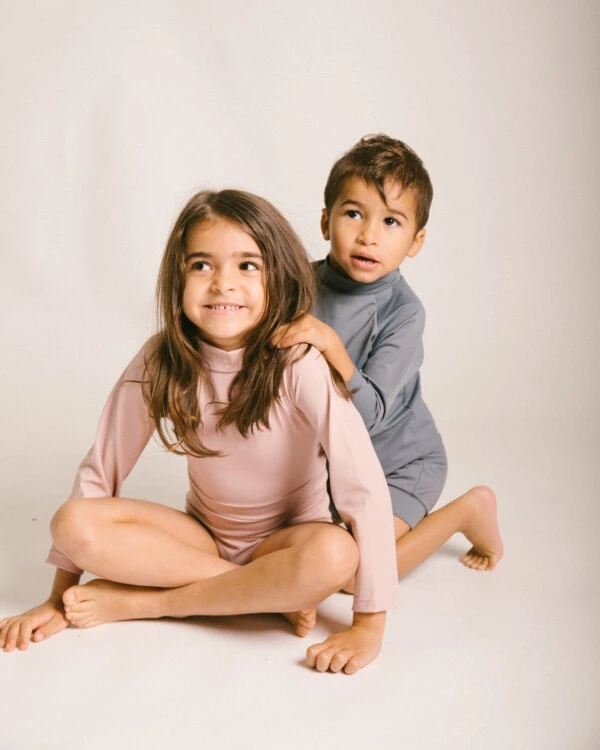 Two children posing for a photo in a June Long Sleeve One-Piece.