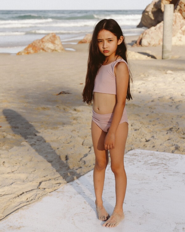 A little girl standing on the beach in an Arla Bikini.