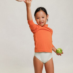 A little girl is holding the Playtime Collection - Nella Rash Shirt - Mandarin in her hand.