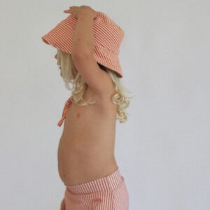 A little girl wearing the Playtime Collection - Lumi Brief Swim Nappy - Mandarin and shorts.