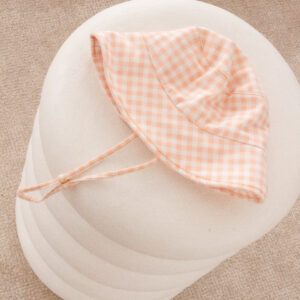A Unisex Vali Bucket Hat - Apricot Gingham on a pillow.
