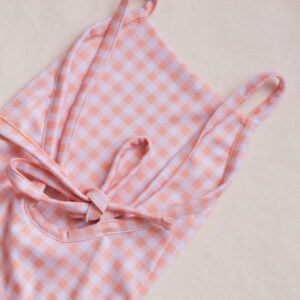 An Azure & Apricot Gingham - Mara One-Piece swimsuit on a white surface.