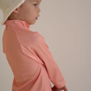 A young boy wearing a hat and the Sorbet Summer - Nella Rash Shirt.