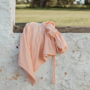 A Sorbet Summer - Summer Poncho hanging on a wall in a field.