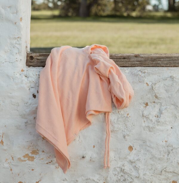 A Sorbet Summer - Summer Poncho hanging on a wall in a field.