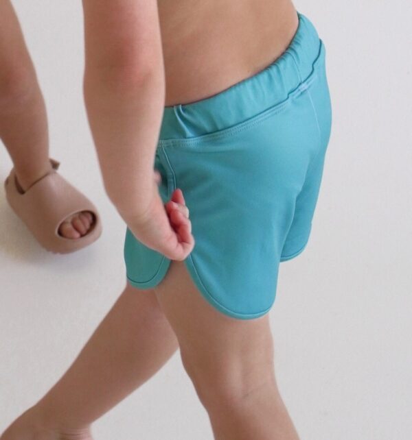 A little girl wearing Sorbet Summer - Mesa Trunks and flip flops.