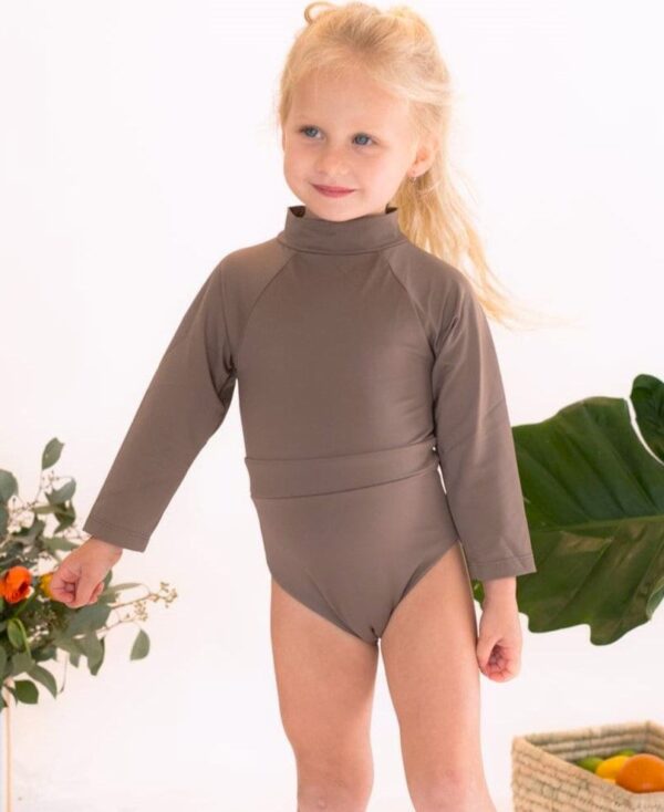 A little girl in a June Long Sleeve One-Piece posing for a photo.