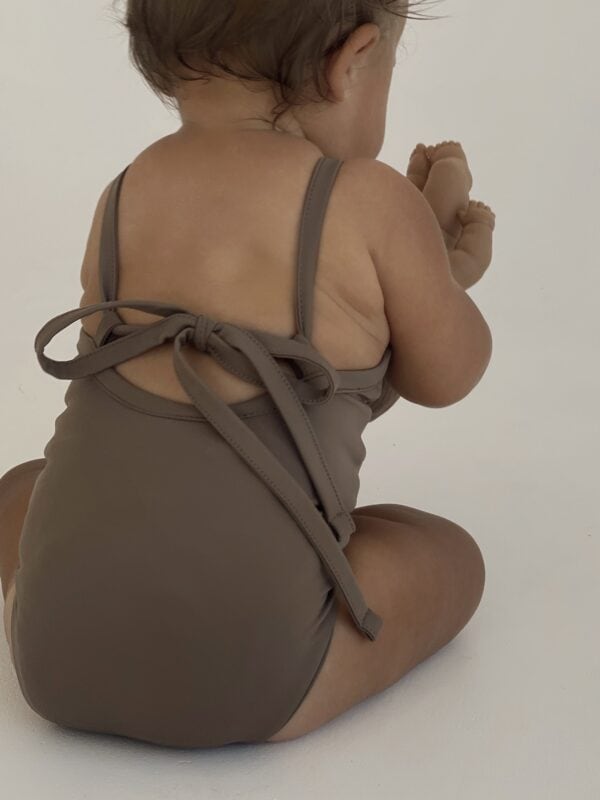 A baby wearing a brown Mara One-Piece swimsuit.