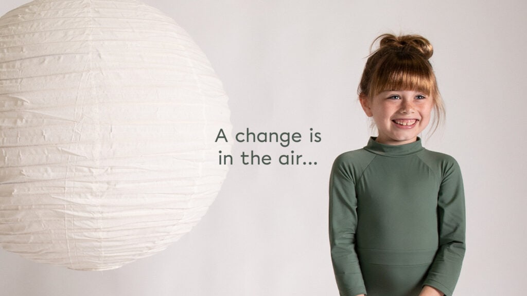 A little girl in eco-friendly swimwear with the words a change is in the air.