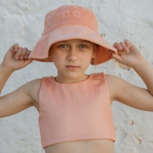 A young girl wearing a peach hat and bikini.