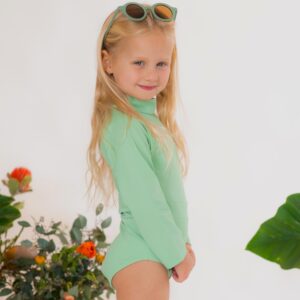 A little girl wearing the Retro Wave By Ina - June One-Piece swimsuit and sunglasses.