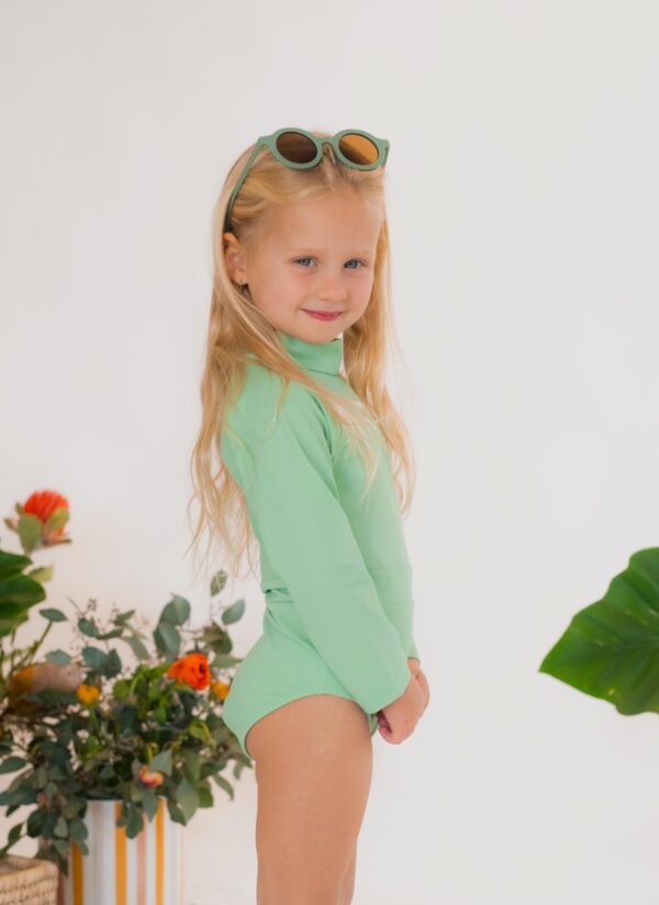 A little girl wearing the Retro Wave By Ina - June One-Piece swimsuit and sunglasses.
