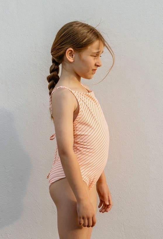 A young girl wearing the Retro Wave By Ina - Mara One-Piece swimsuit.