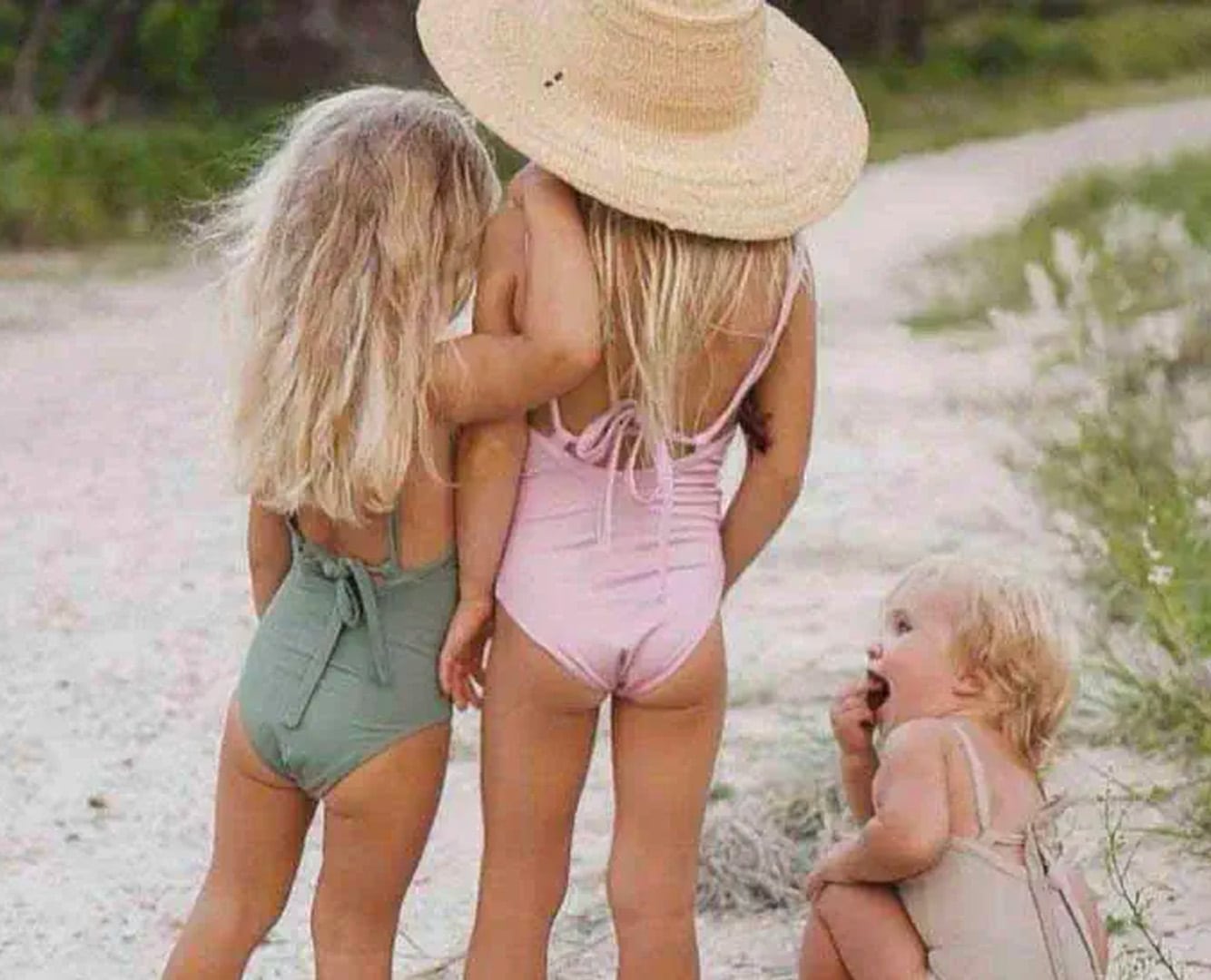 Three little girls in sustainable swimwear on the beach.
