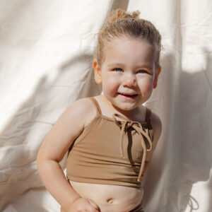 Toddler in a Luna Bikini - Warm Pecan swimsuit smiling.